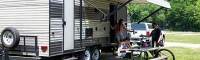 man and 2 women hanging out outside of RV. 